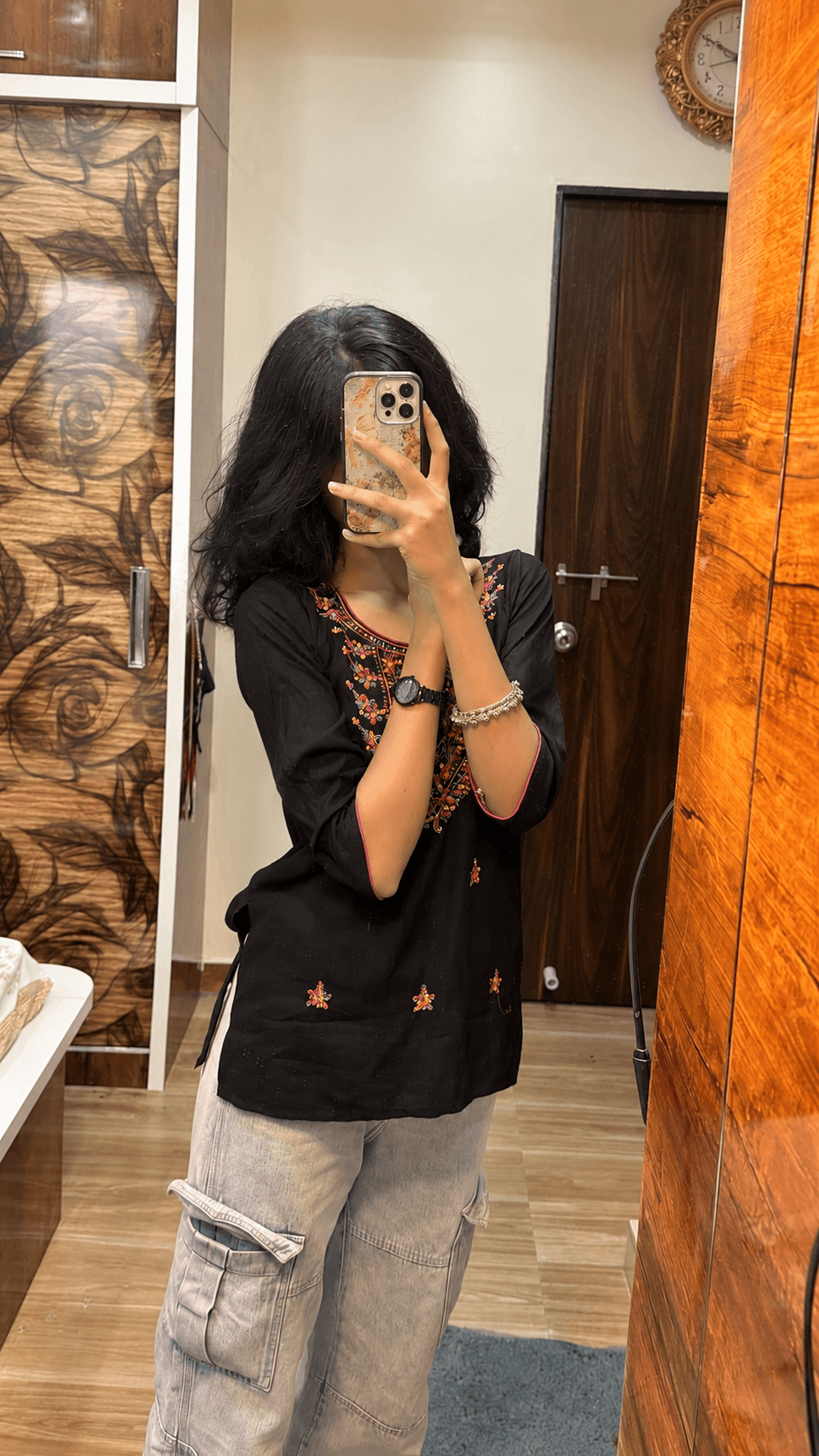 Mirror selfie featuring a floral Pinterest-inspired glass phone case with a black ethnic outfit.